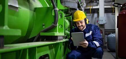 Man looking at an iPad next to a gas engine 