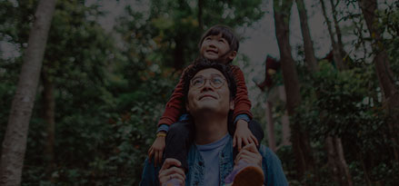 Child on a man shoulders in a forest