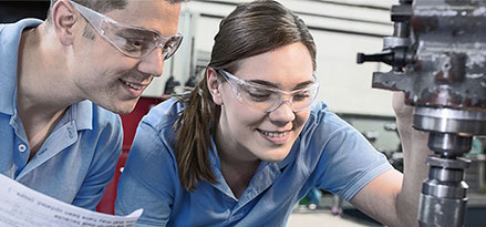 Mobil worker and customer looking at a guage on a machine against a document