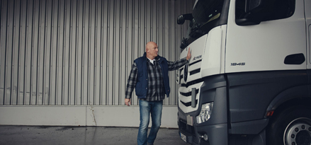 Lorry driver tapping the front of his lorry in a warehouse