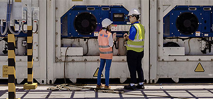 Mobil worker and customer looking at guage on outside a factory