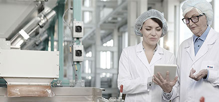 Mobil worker and customer looking at an iPad in a food factory