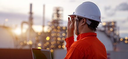 Worker holding a laptop overlooking a power plant