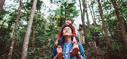 Father carrying his child through a forest