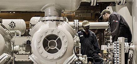 Mobil worker and customer looking at a large gas compressor