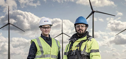 Mobil worker and customer in front of wind turbines